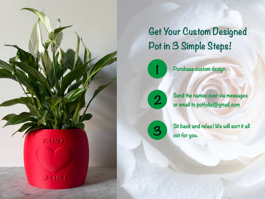 Potted plant in a red Potfolia plant pot with embossed heart and names on a marble surface