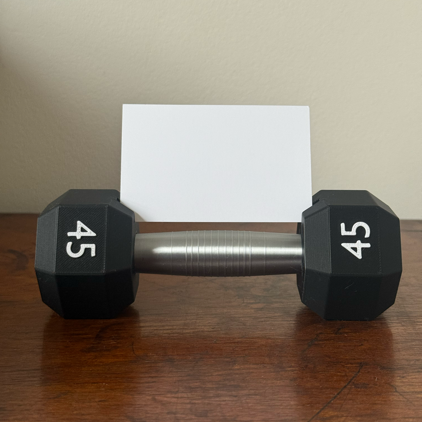 Dumbbell shape design business card holder with a plain background on a wooden surface