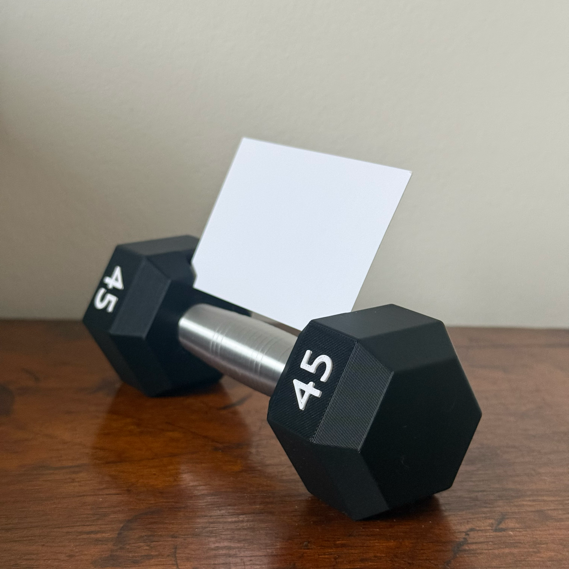 Dumbbell shape design business card holder with a plain background on a wooden surface side profile 