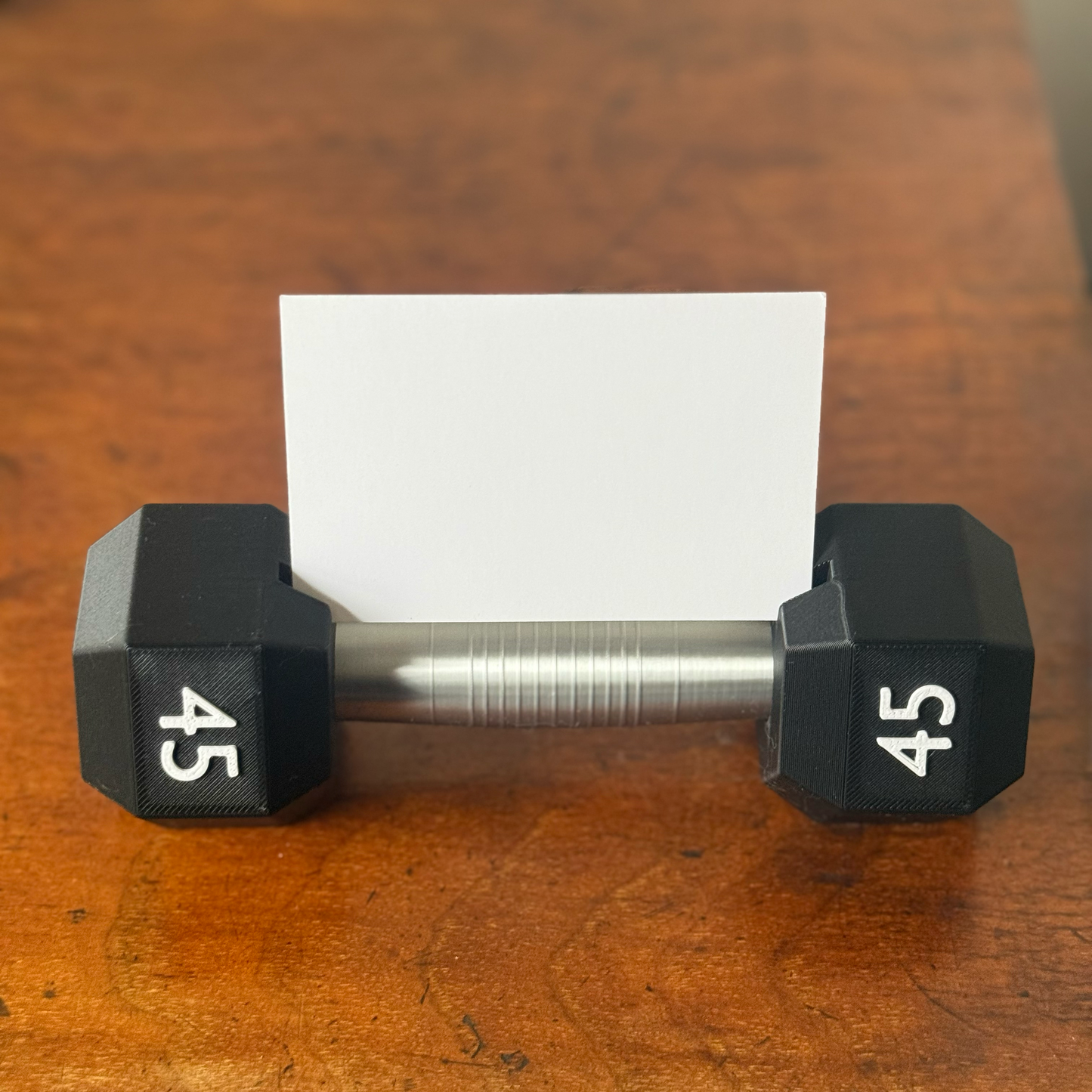 Dumbbell shape design business card holder with a plain background on a wooden surface