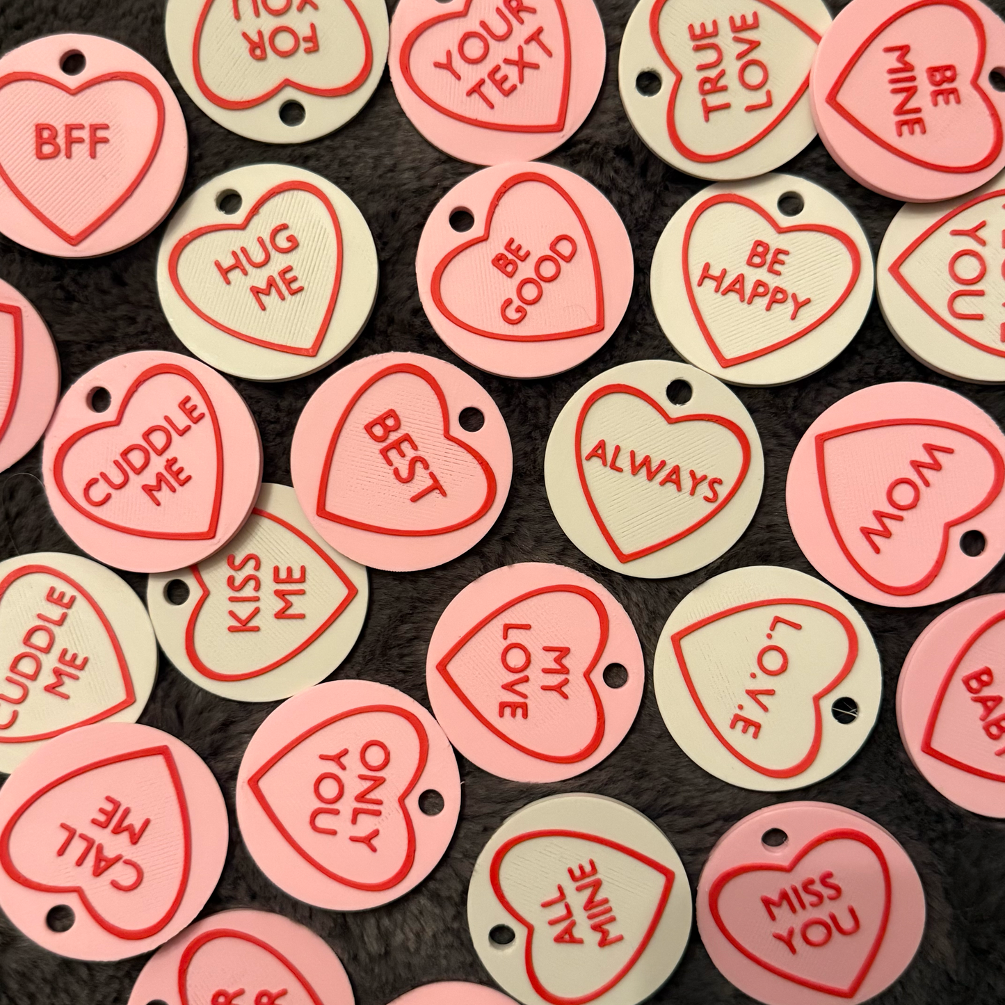 Heart-shaped tokens with various sentiments on a dark background