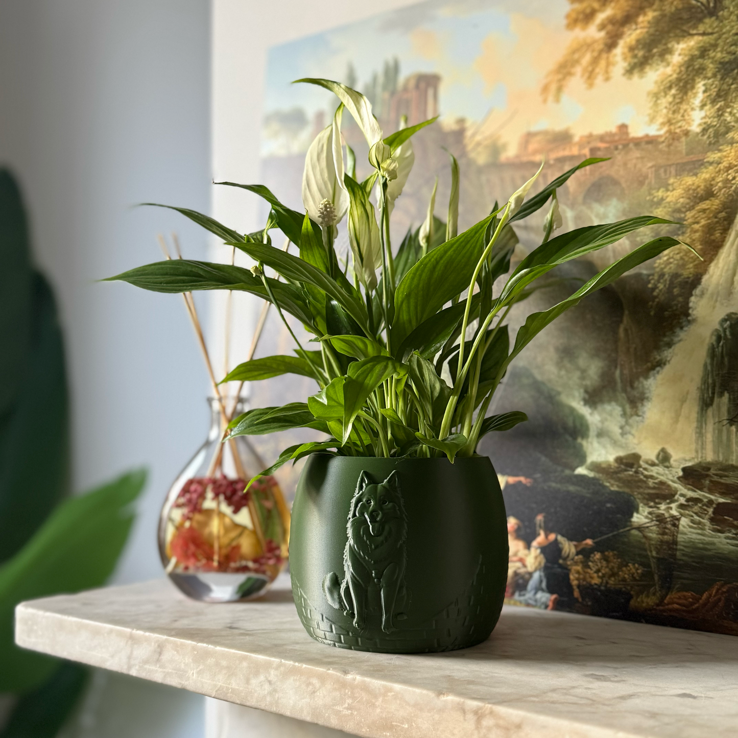 Green potted plant in a green plant pot with an embossed Husky standing on a marble surface