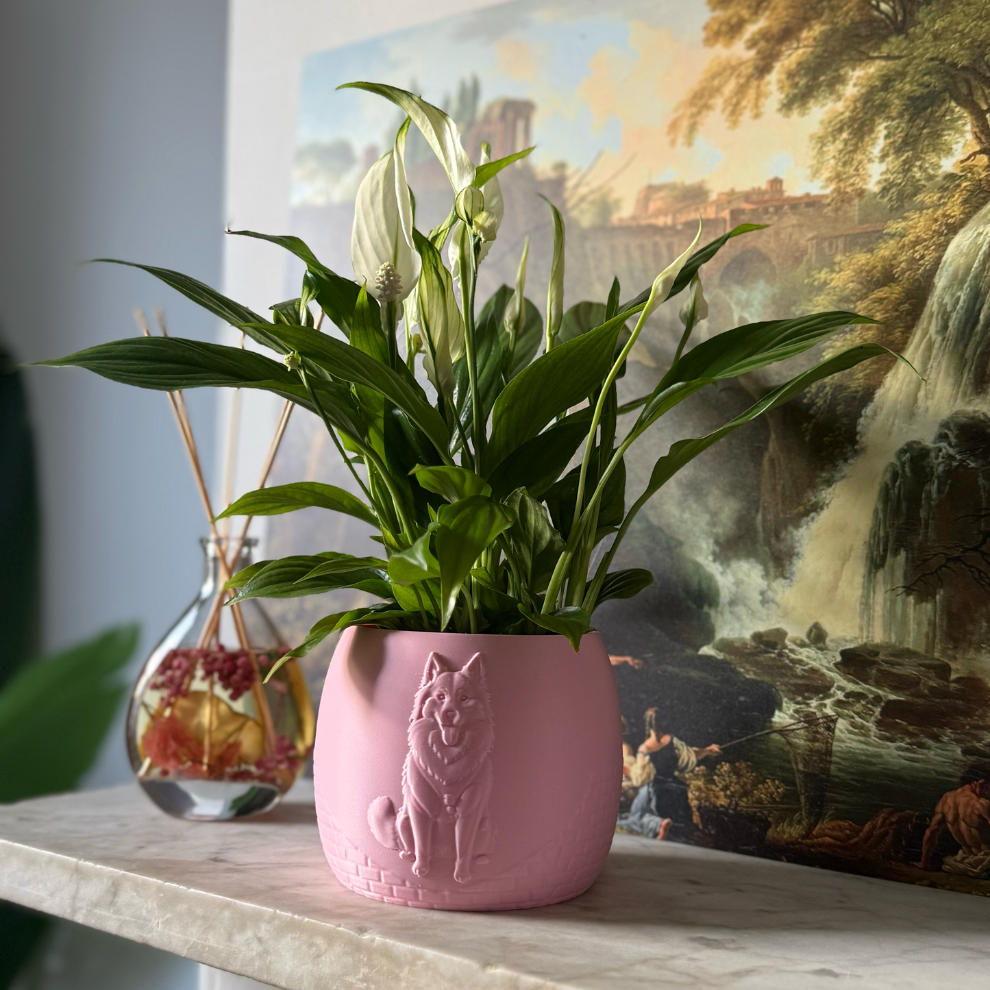 Green potted plant in a pink plant pot with an embossed Husky standing on a marble surface