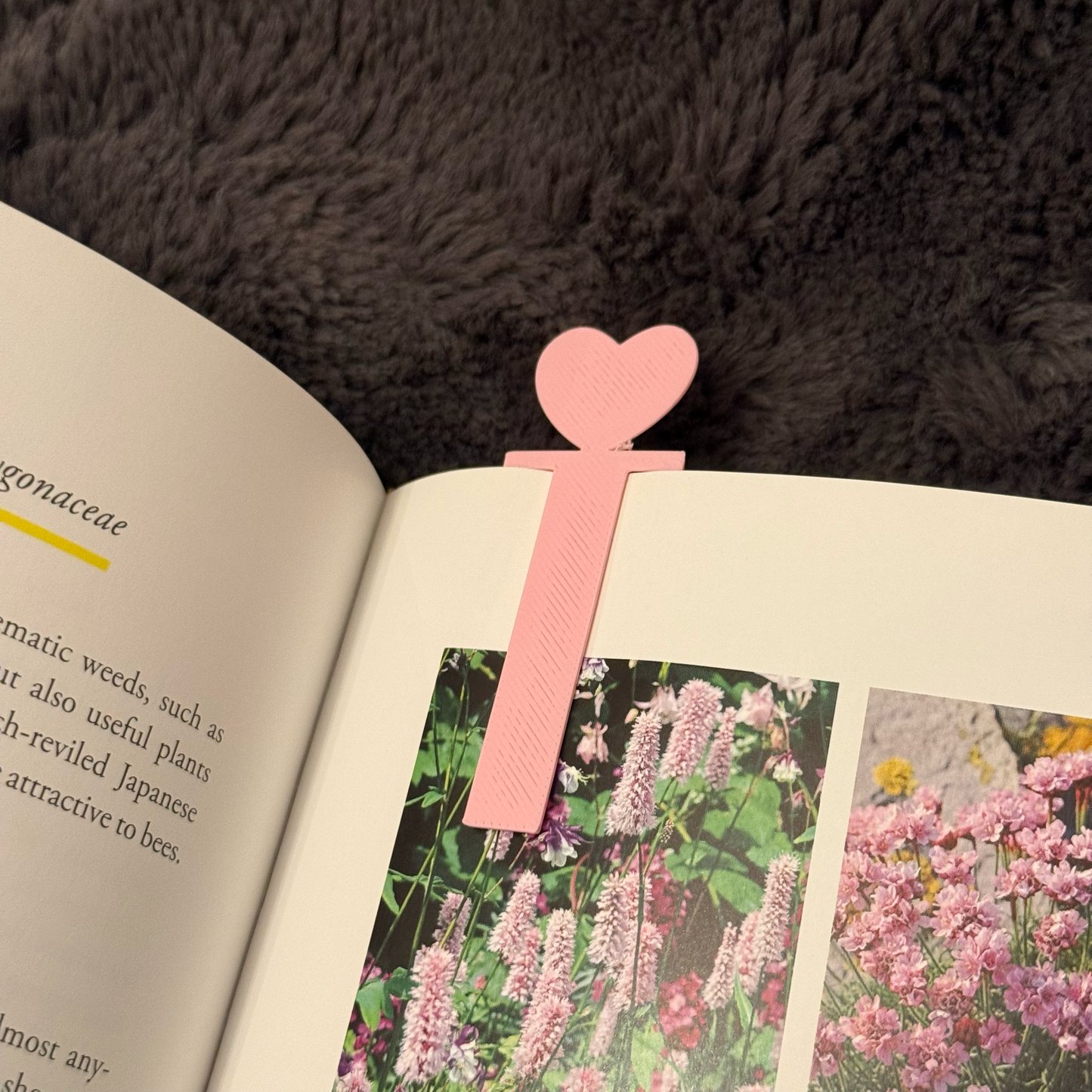 Pink heart-shaped bookmark on an open book with floral illustrations
