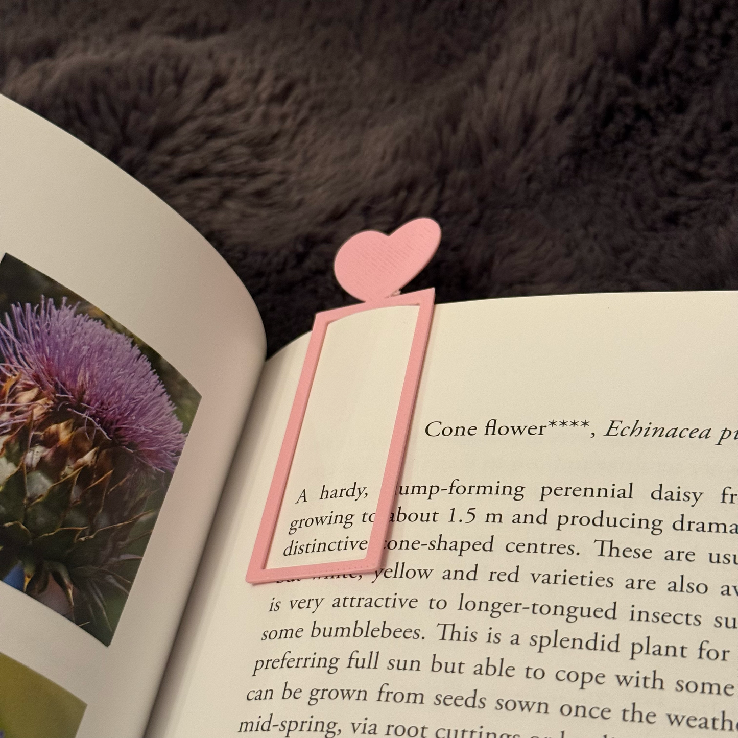 Pink heart-shaped bookmark on an open book with a fur background