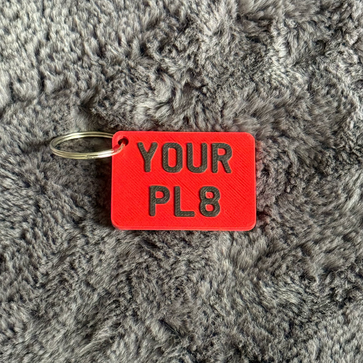 Red tag with 'YOUR PL8' text on a textured gray surface