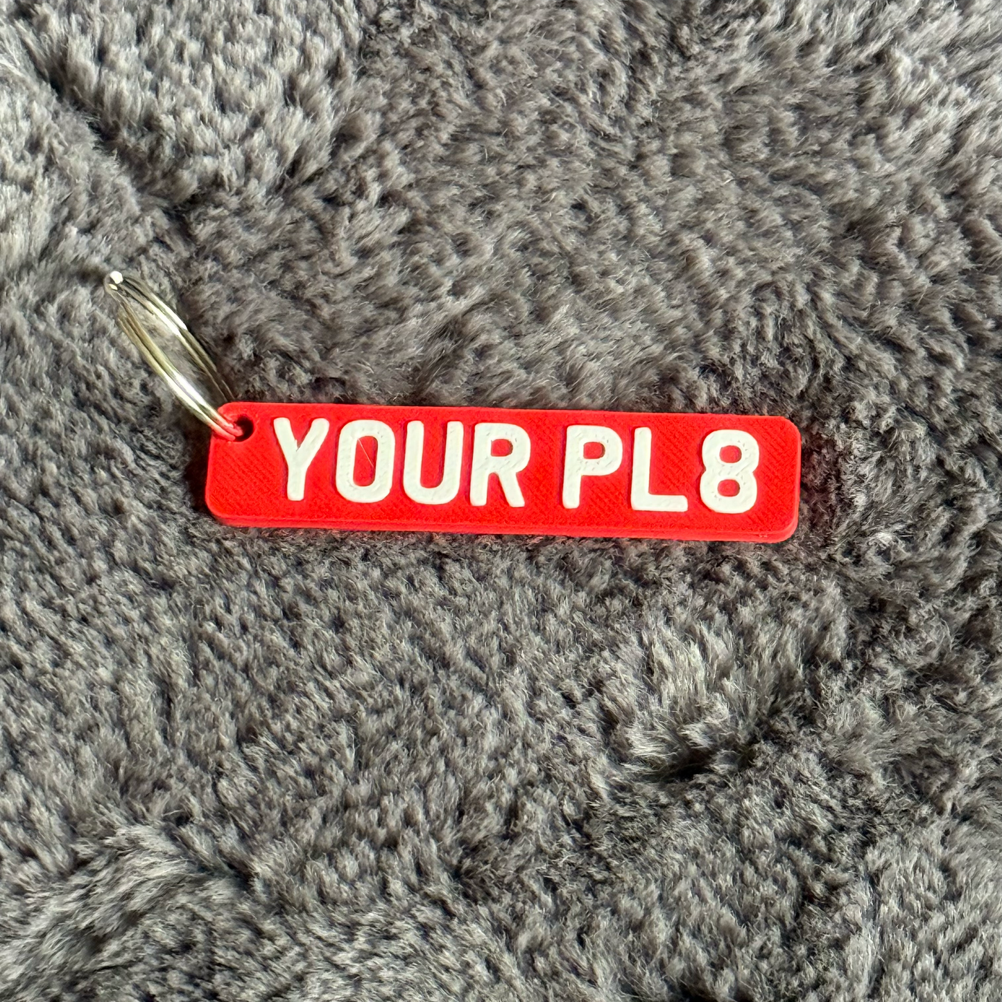 Red tag with 'YOUR PL8' text on a gray textured surface