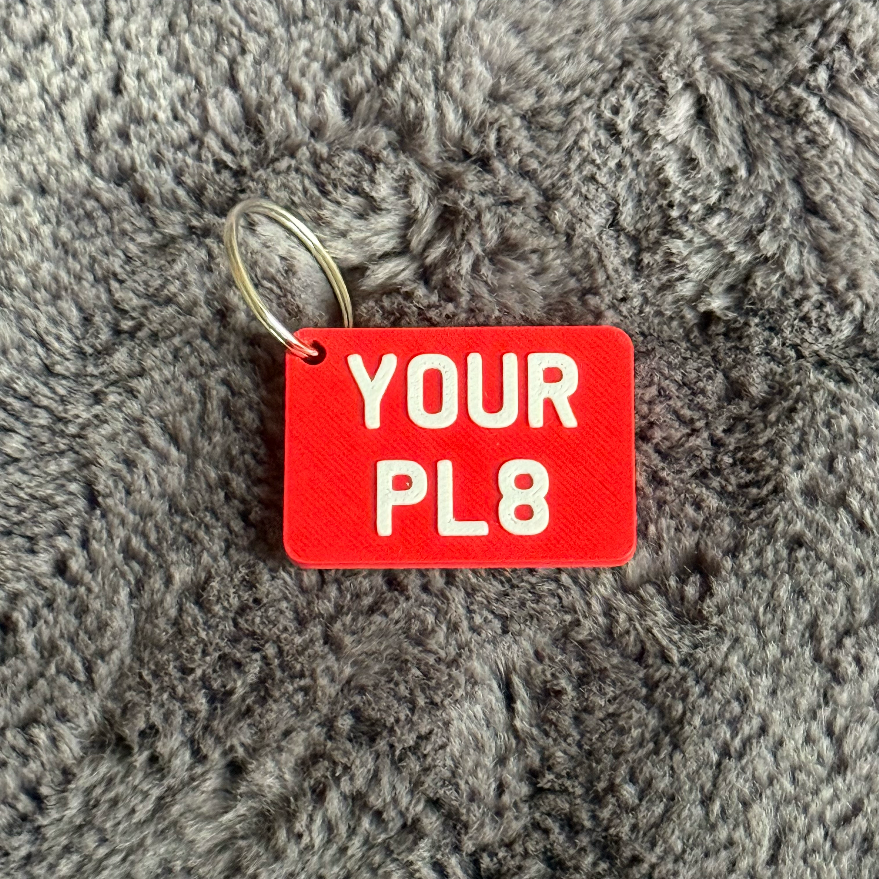 Red tag with 'YOUR PL8' text on a gray textured surface
